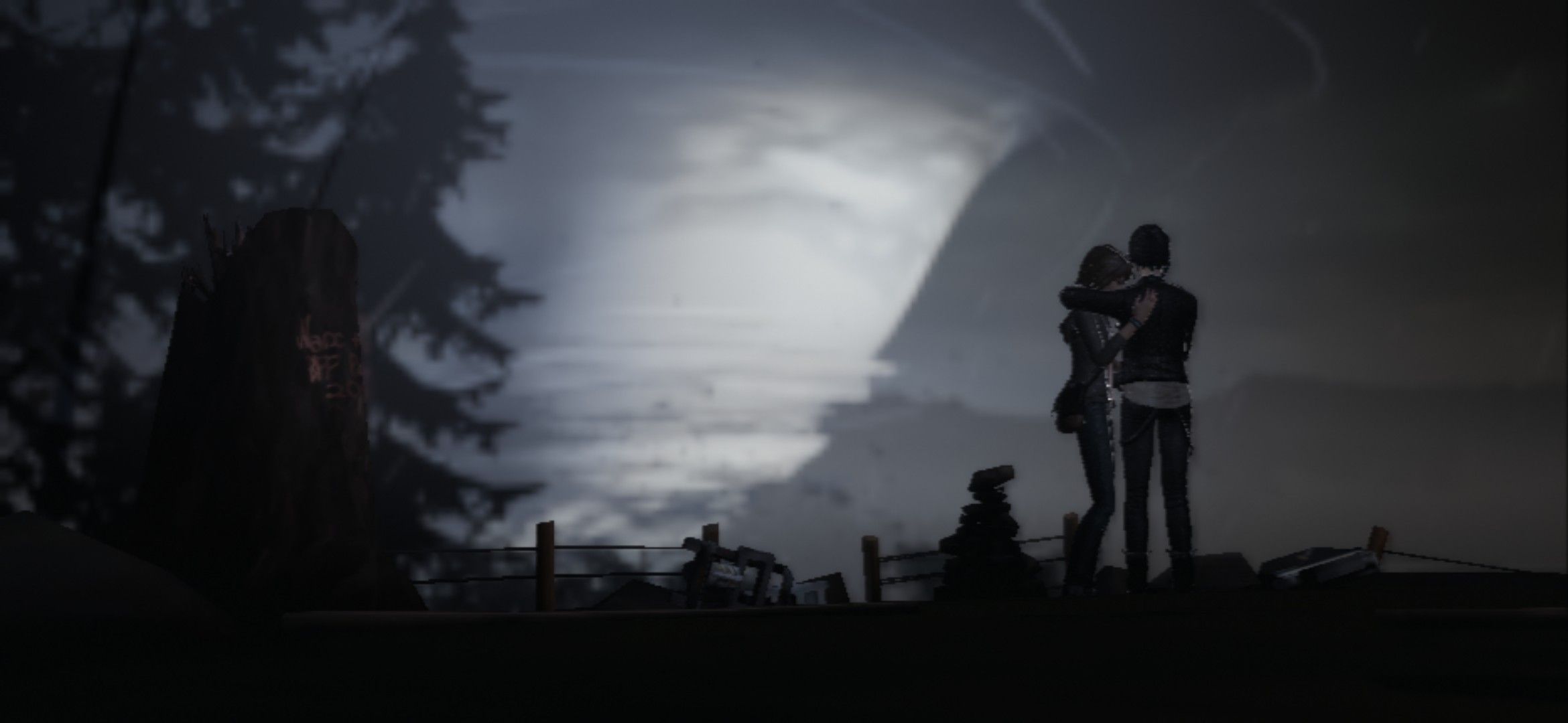A screenshot from Life is Strange (2015) in which Max and Chloe hold each other, standing on a cliff, watching the tornado approach